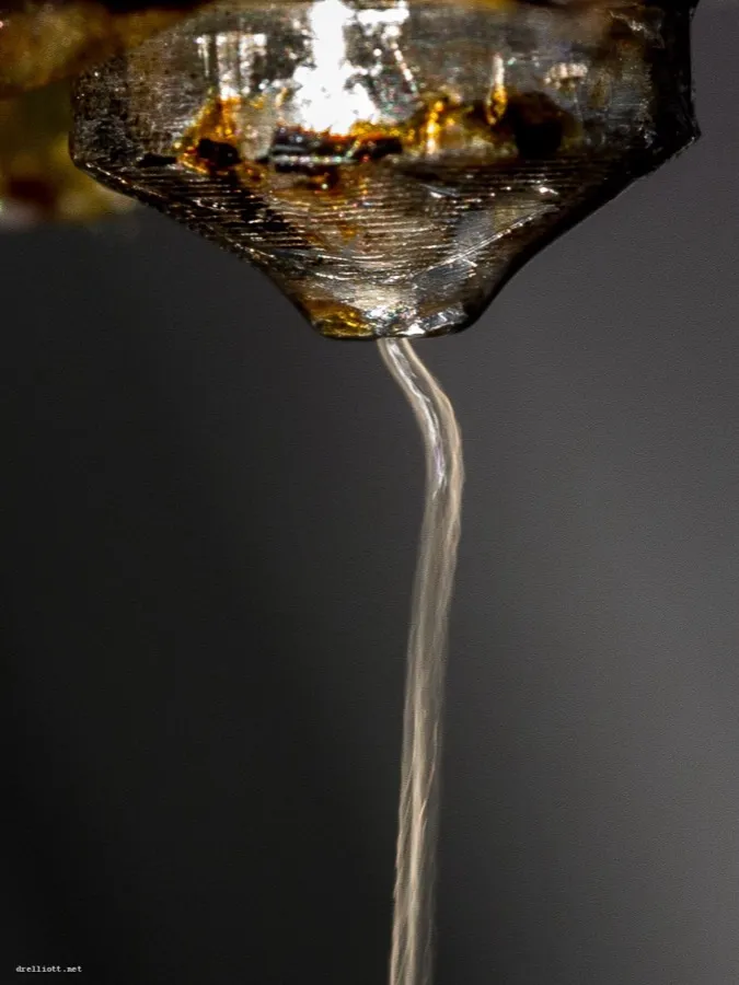 Bico de impressora 3D soltando o fio de plástico derretido